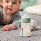 baby using b.box baby bottle handles to support independent self-feeding