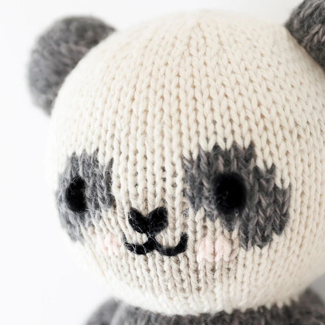 Close up of Cuddle+Kind baby panda knit plush toy showing stitched face details