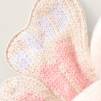 Close up of Cuddle+Kind baby butterfly plush toy showing embroidered face and patterned pink wings