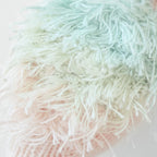 Close up of Cuddle+Kind baby parrot showing fluffy textured knit wings and stitched details in mauve yarn