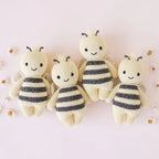 Cuddle+Kind baby bee knit plush toy styled with coordinating hand knit baby animals in a pastel nursery setting