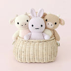 Cuddle+Kind baby cow plush toy displayed with matching nursery accessories in soft pink tones