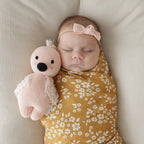 Baby cuddling Cuddle+Kind baby flamingo soft knit plush toy during playtime