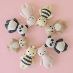 Cuddle+Kind baby bee knit plush toy styled with coordinating hand knit baby animals in a pastel nursery setting