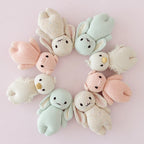 Cuddle+Kind baby bunny (confetti) plush toy displayed with coordinating hand knit animals in soft pastel tones
