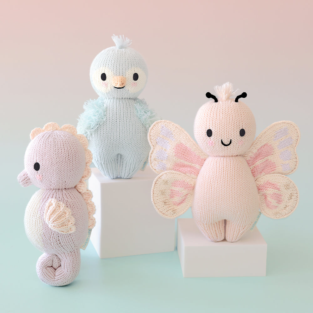 Cuddle+Kind baby seahorse knit plush toy styled with coordinating hand knit baby animals in a pastel nursery setting