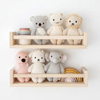 Cuddle+Kind hand knit stuffed animal collection displayed on nursery shelf including baby elephant, baby kitten, baby lamb, baby lion, baby flamingo and baby koala