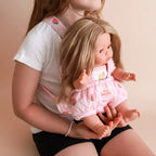 kid wearing the baby dolls carrier made by tiny harlow with baby inside. good for pretend play, the print is strawberry picnic