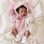 Baby cuddling Cuddle+Kind baby bunny (confetti) soft knit plush toy during playtime