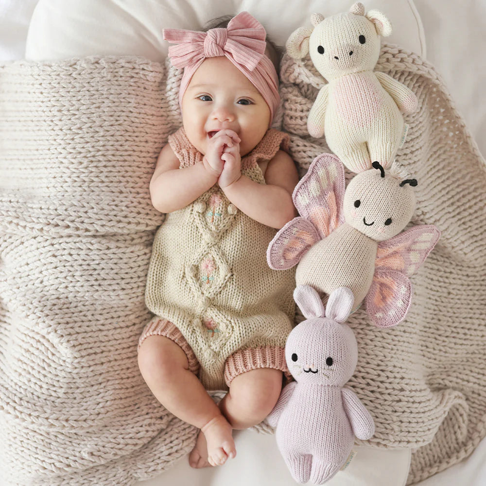 Baby cuddling Cuddle+Kind baby cow soft knit plush toy during playtime