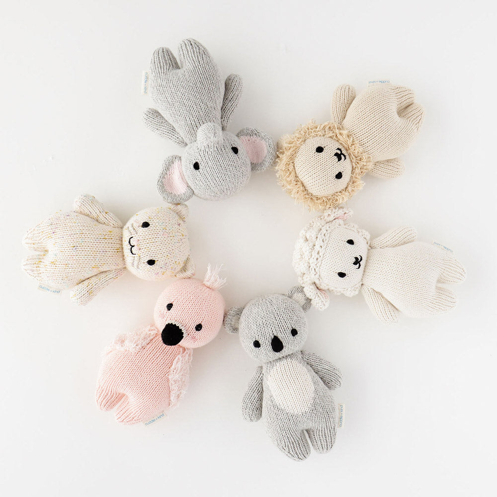 Cuddle+Kind baby elephant knit plush toy with baby lion, baby kitten, baby lamb, baby flamingo and baby koala styled flat lay with nursery accessories