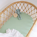 Snuggle Hunny mint organic bassinet sheet fitted on a woven bassinet with soft neutral nursery styling and baby toy