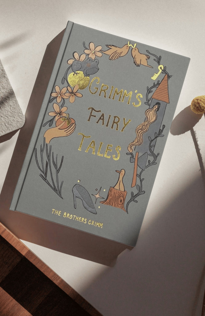 in sun Grimm’s Fairy Tales collector’s edition hardback book with illustrated cover and gold foil lettering featuring classic fairytale stories