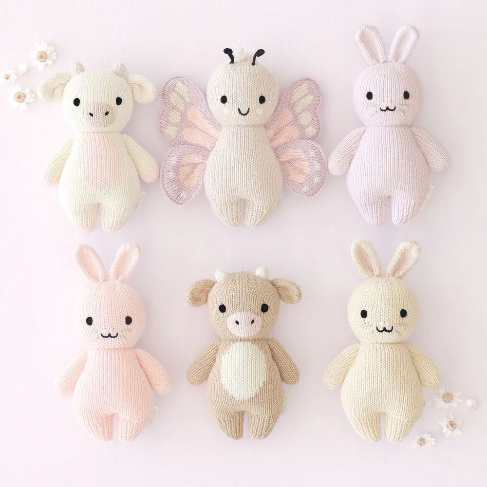Cuddle+Kind hand knit baby animal plush toy collection arranged together in soft pastel nursery decor