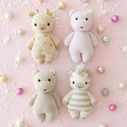 Cuddle+Kind hand knit baby animal plush toys styled together in pastel nursery setting - including baby giraffe, baby zebra
