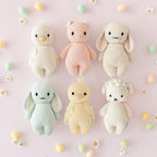 Cuddle+Kind baby animal collection of hand knit plush toys arranged together in pastel nursery setting (including baby gosling, baby bunny in mint and speckle, baby duckling and baby lamb.