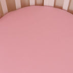 Bubblegum pink organic cotton fitted cot sheet laid flat showing smooth soft jersey fabric and solid pastel colour