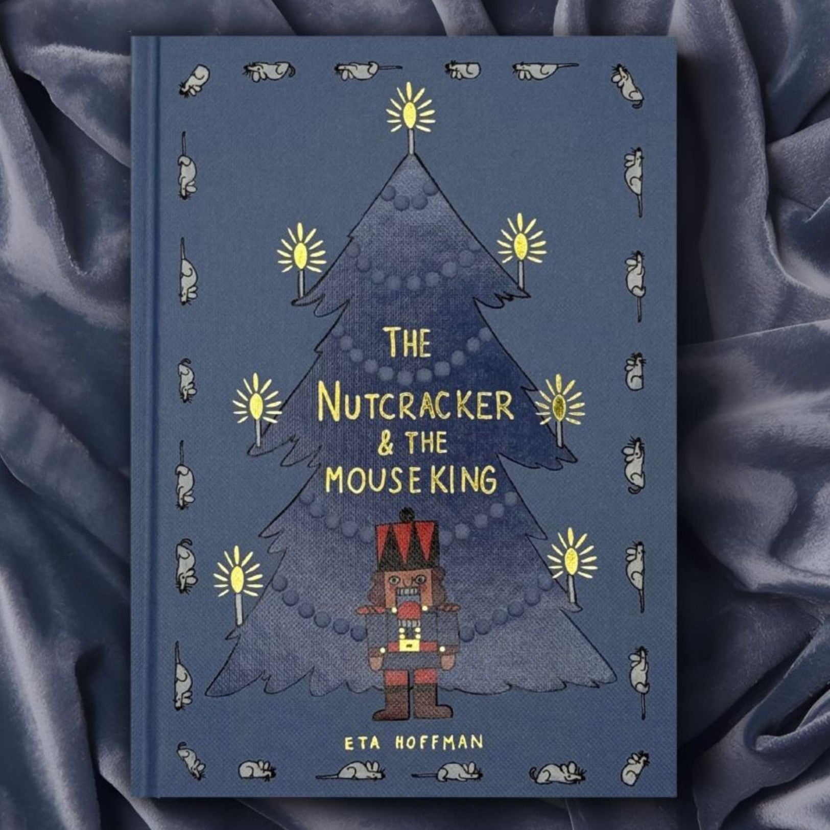 photoshoot of The Nutcracker & The Mouse King collector’s edition hardcover book with blue illustrated cover, gold foil title, festive Christmas design.