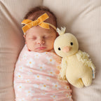 Baby cuddling Cuddle+Kind baby duckling soft knit plush toy during playtime