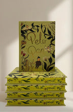 sprayed edges Peter Pan limited collector’s edition hardcover by J.M. Barrie with green illustrated cover, gold foil title, cloth-bound finish and decorative sprayed edges, stacked on books.