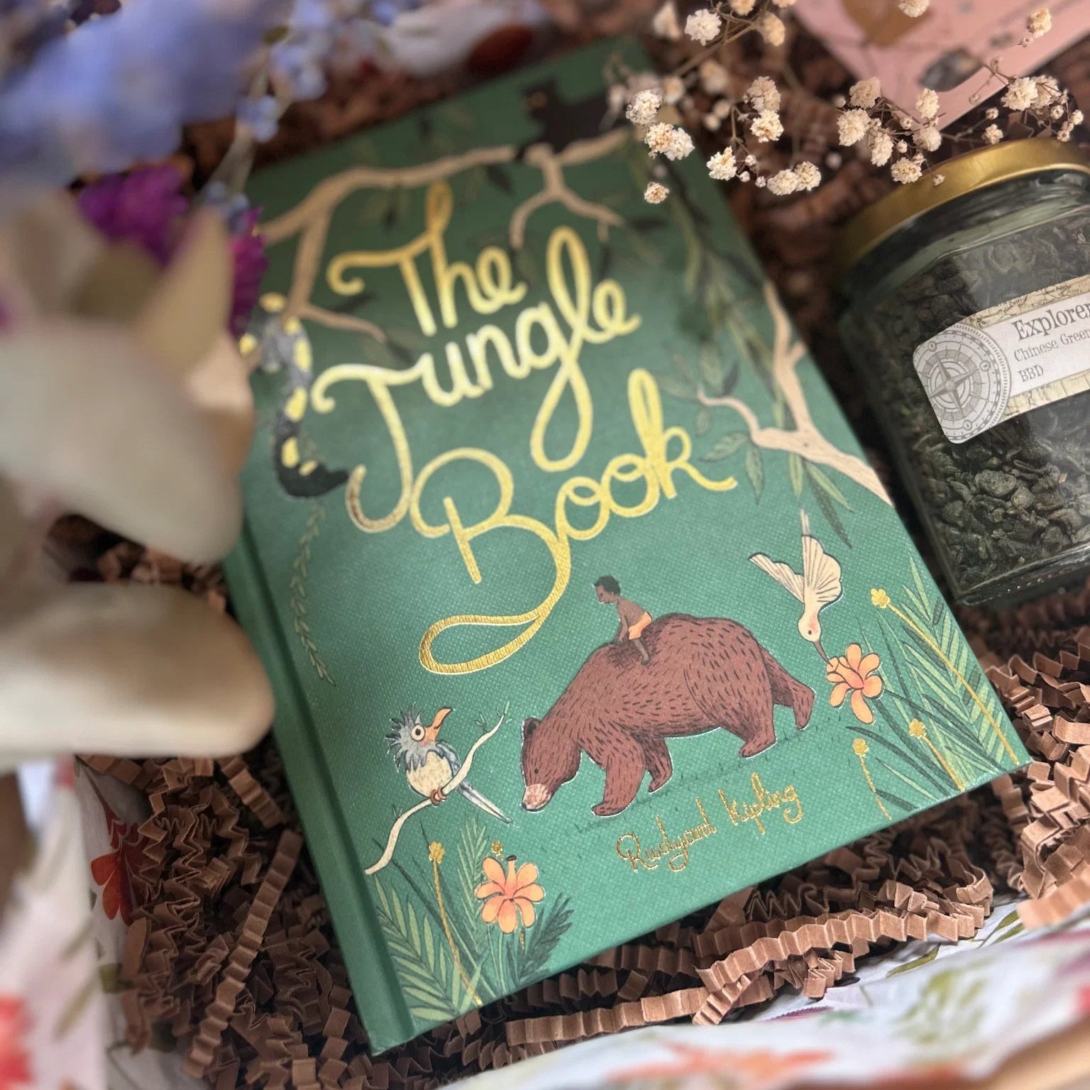 in gift box limited edition The Jungle Book collector’s edition hardcover by Rudyard Kipling with green illustrated cover, gold foil title, cloth-bound finish and decorative sprayed edges, stacked on books.