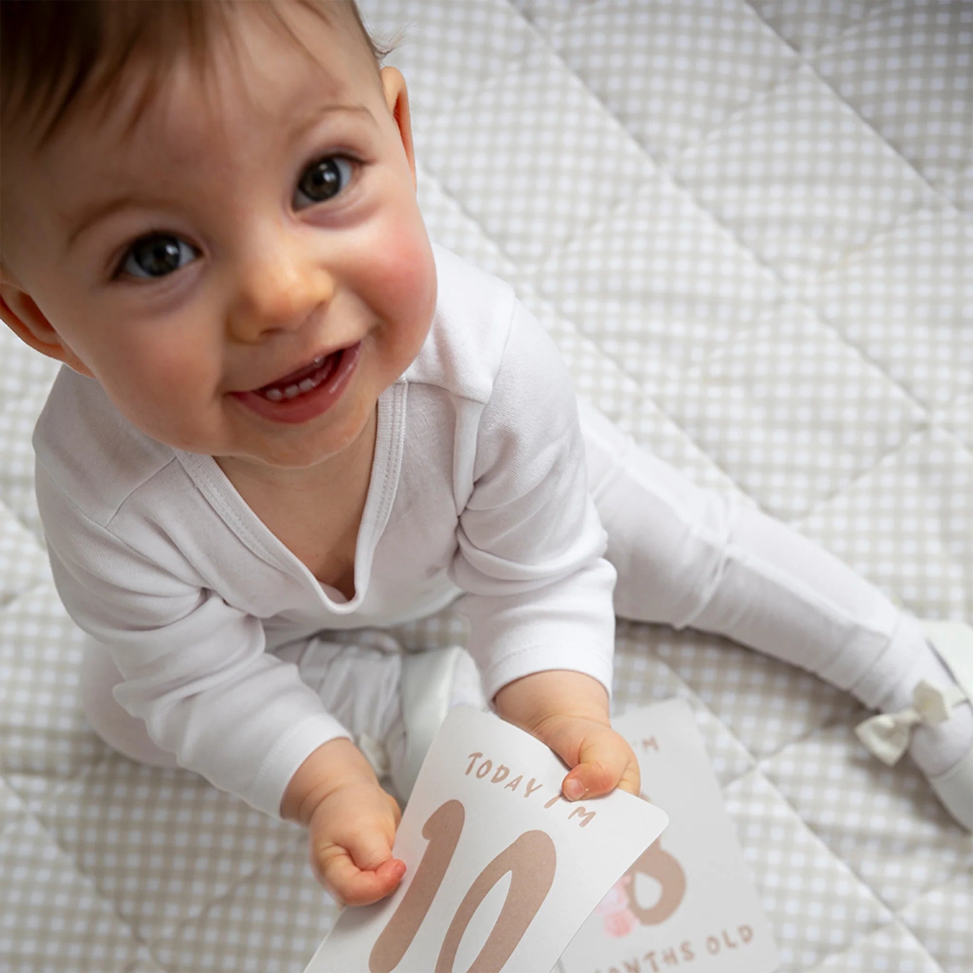 baby playing with milestone cards by lively living to track babies age and milestones. great for photos and theme is tractor ride. card pictured reads today i'm 10 months old