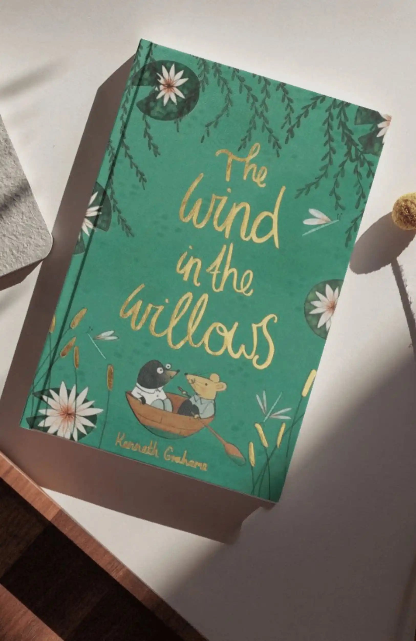 photoshoot of The Wind in the Willows collector’s edition hardback book with green illustrated cover and gold foil lettering by Kenneth Grahame