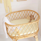 Lemon Sorbet bassinet sheet styled in natural rattan bassinet showing snug stretch fit and breathable organic cotton fabric