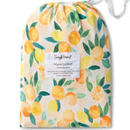 Snuggle Hunny Sunny Citrus organic fitted cot sheet in matching drawstring bag featuring bright lemon and citrus fruit print