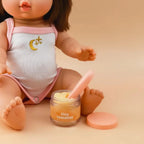 a mini coletto doll showcasing the tiny tummies pretend play doll food jars that disappear like real food. brand is tiny harlow and tiny tummies food jar flavour is banana custard