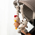 Living Textiles cow and chicken stroller toys attached to a baby pram for on-the-go play