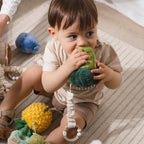 Child playing with Living Textiles broccoli and tomato plush stroller toys