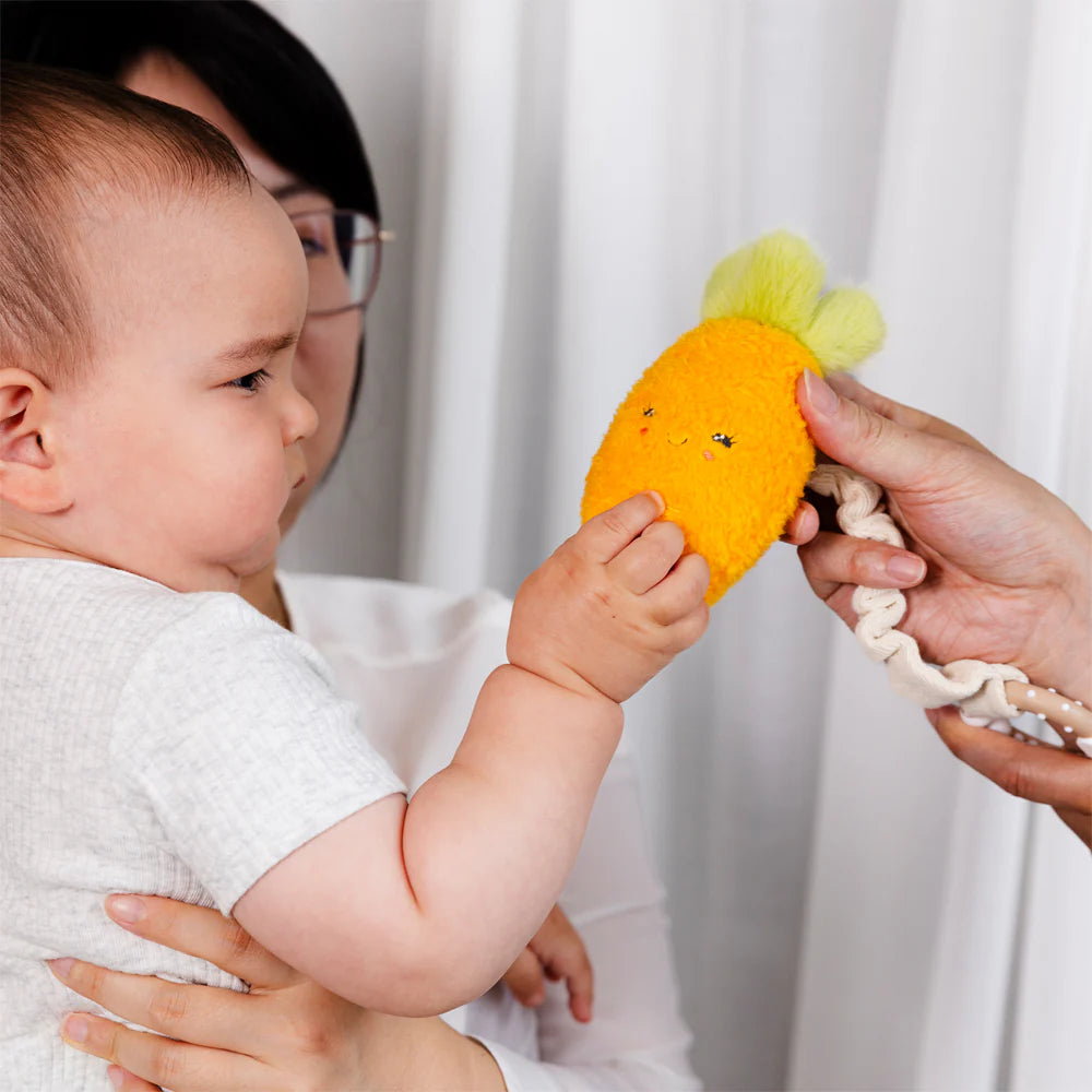 Baby holding Living Textiles carrot mini market plush toy