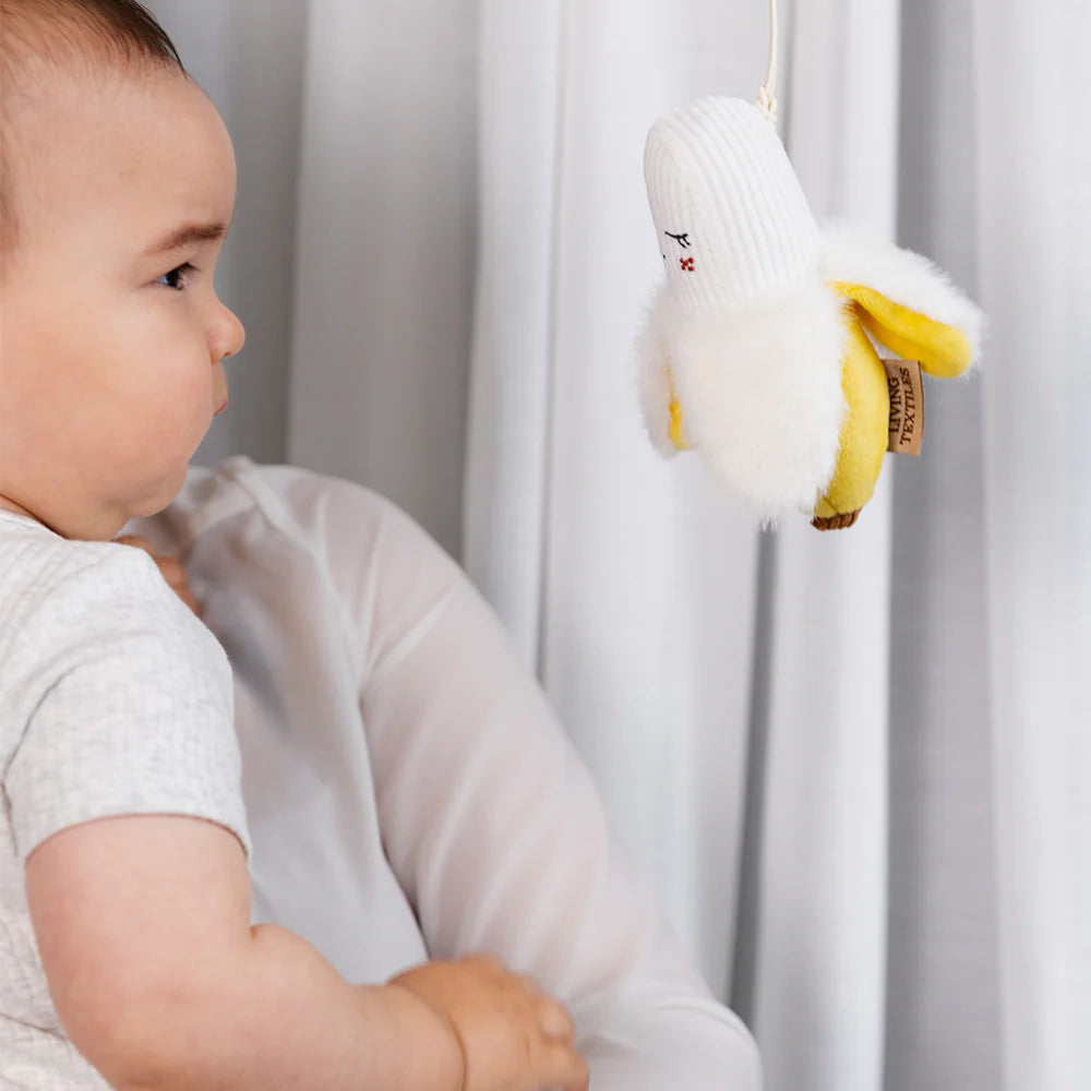 Baby holding Living Textiles banana plush stroller toy