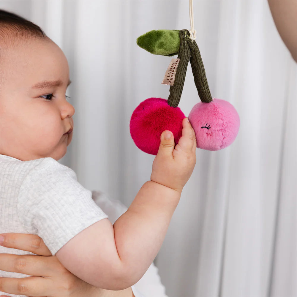 Baby playing with Living Textiles pineapple and cherries hanging stroller toys
