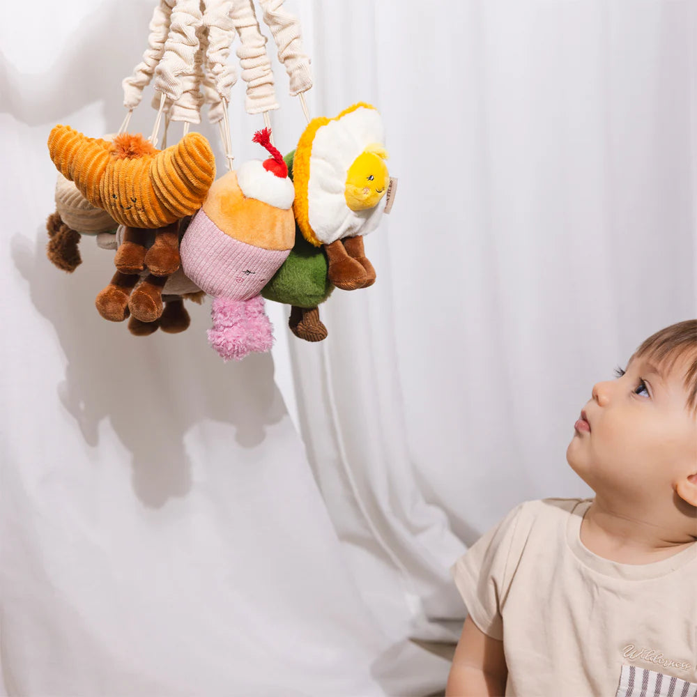 Baby reaching for Living Textiles avocado and egg stroller toys