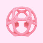 A pink textured silicone baby teether toy with a circular design, featuring textured grips, ridges, and circular suction cups on a plain white background.