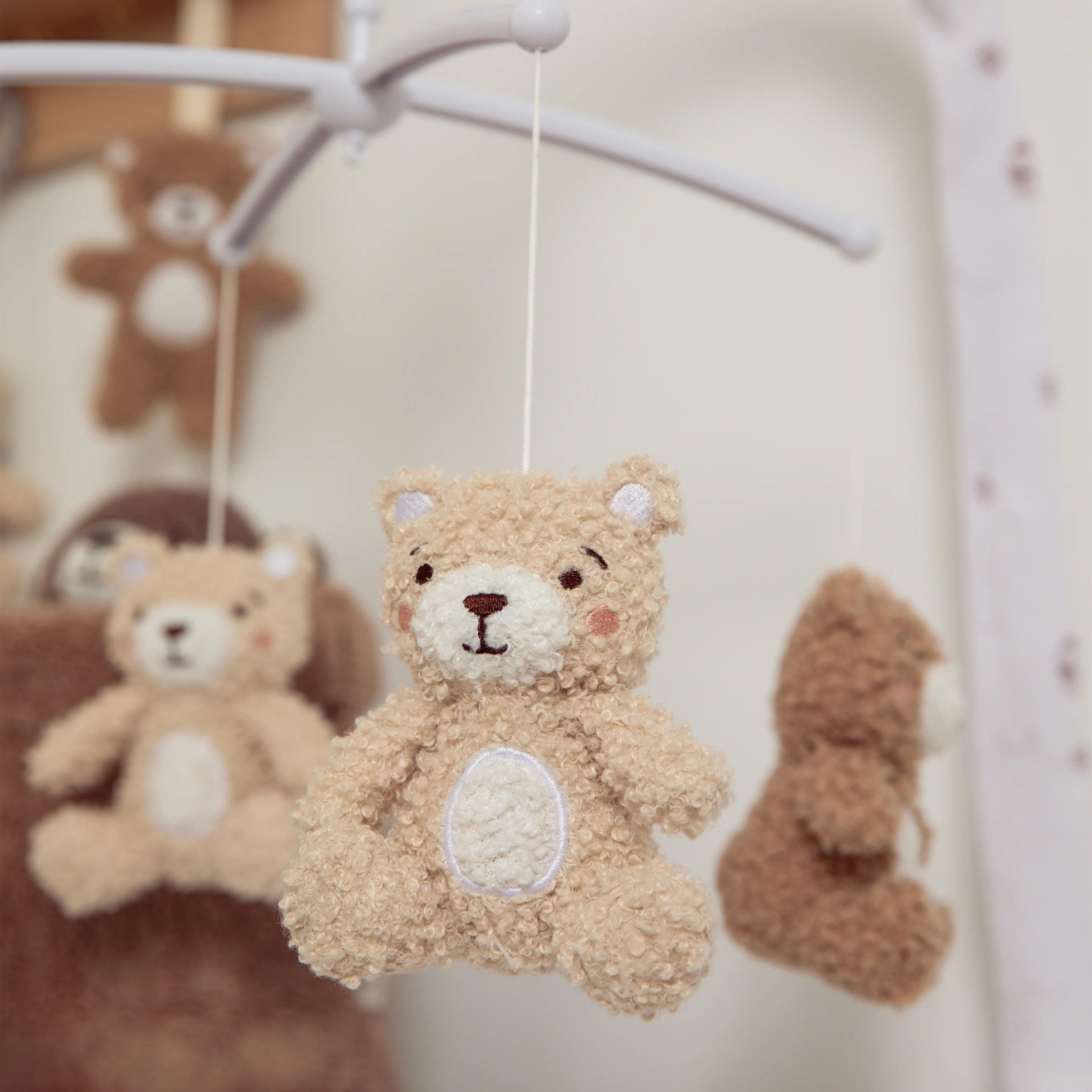 Teddy bear toy hanging from a mobile with a blurred background