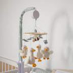 Baby mobile with ducks and a bee hanging from it in a crib.