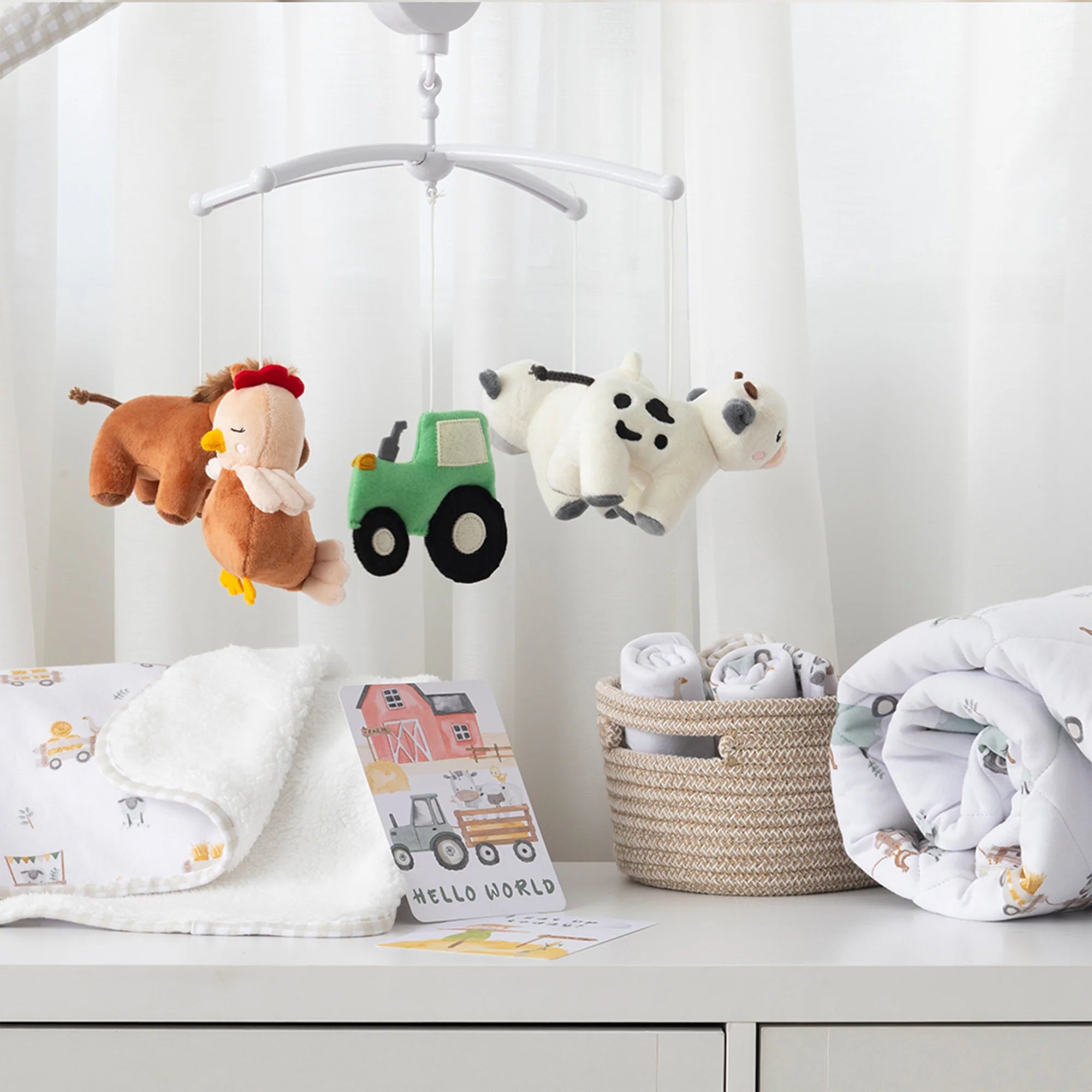 Baby mobile with plush toys and baby items on a white dresser.