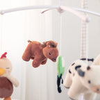 Plush animal toys hanging from a crib mobile against a white background