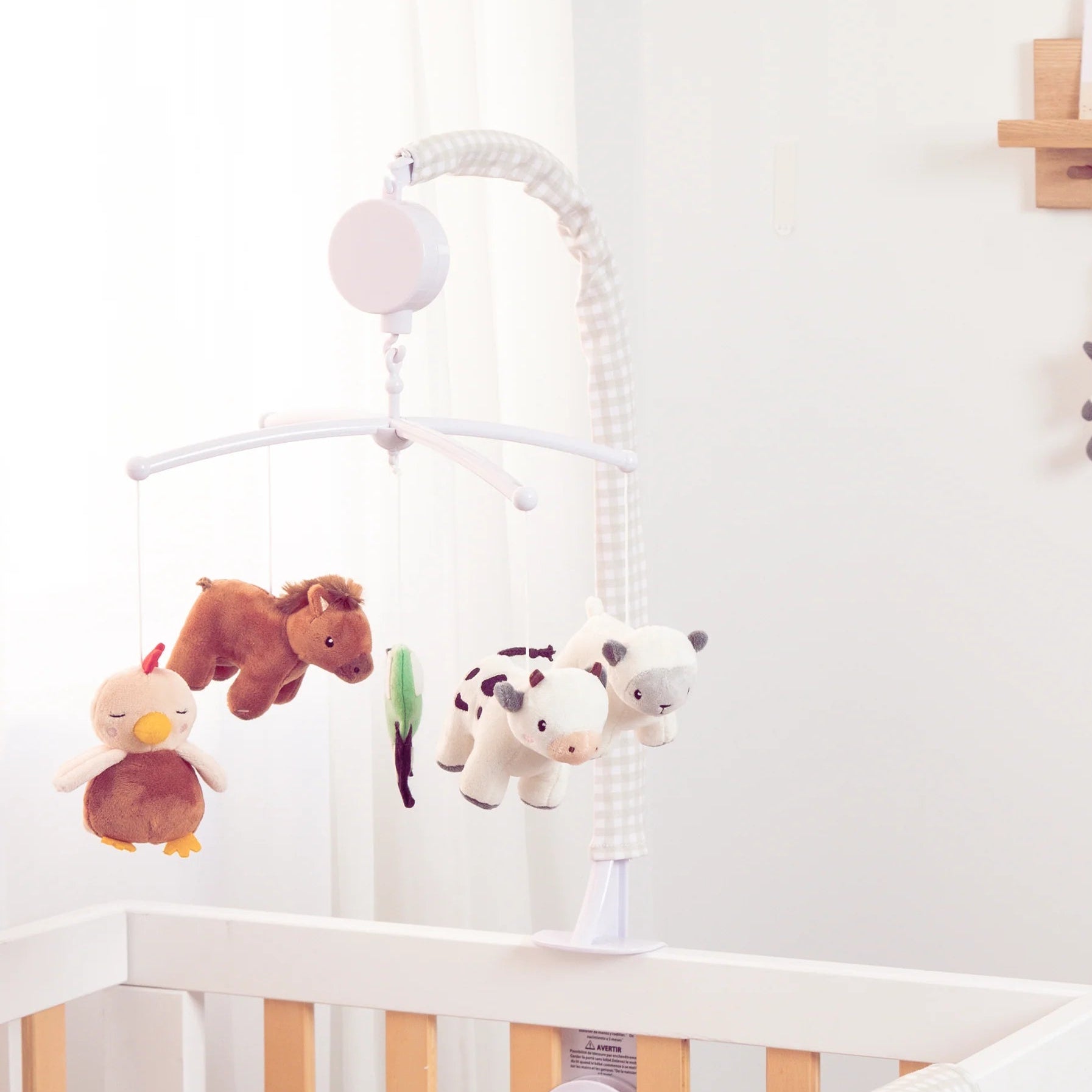 Nursery room with crib, toys, and hanging items on a white wall.
