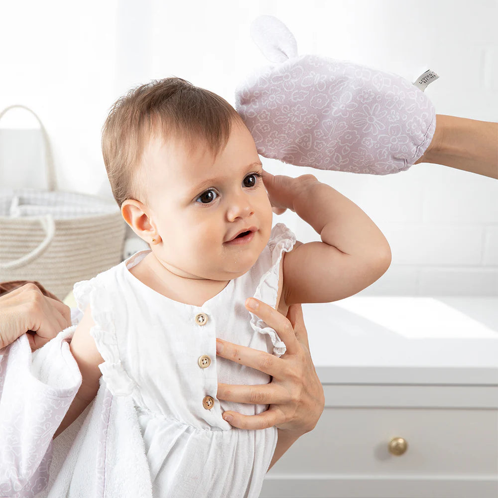 Baby in a white outfit with a white background and bath mitt