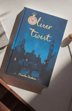 photoshoot of  Oliver Twist collector’s edition hardcover by Charles Dickens with navy blue illustrated cover, gold foil title, cloth-bound finish.