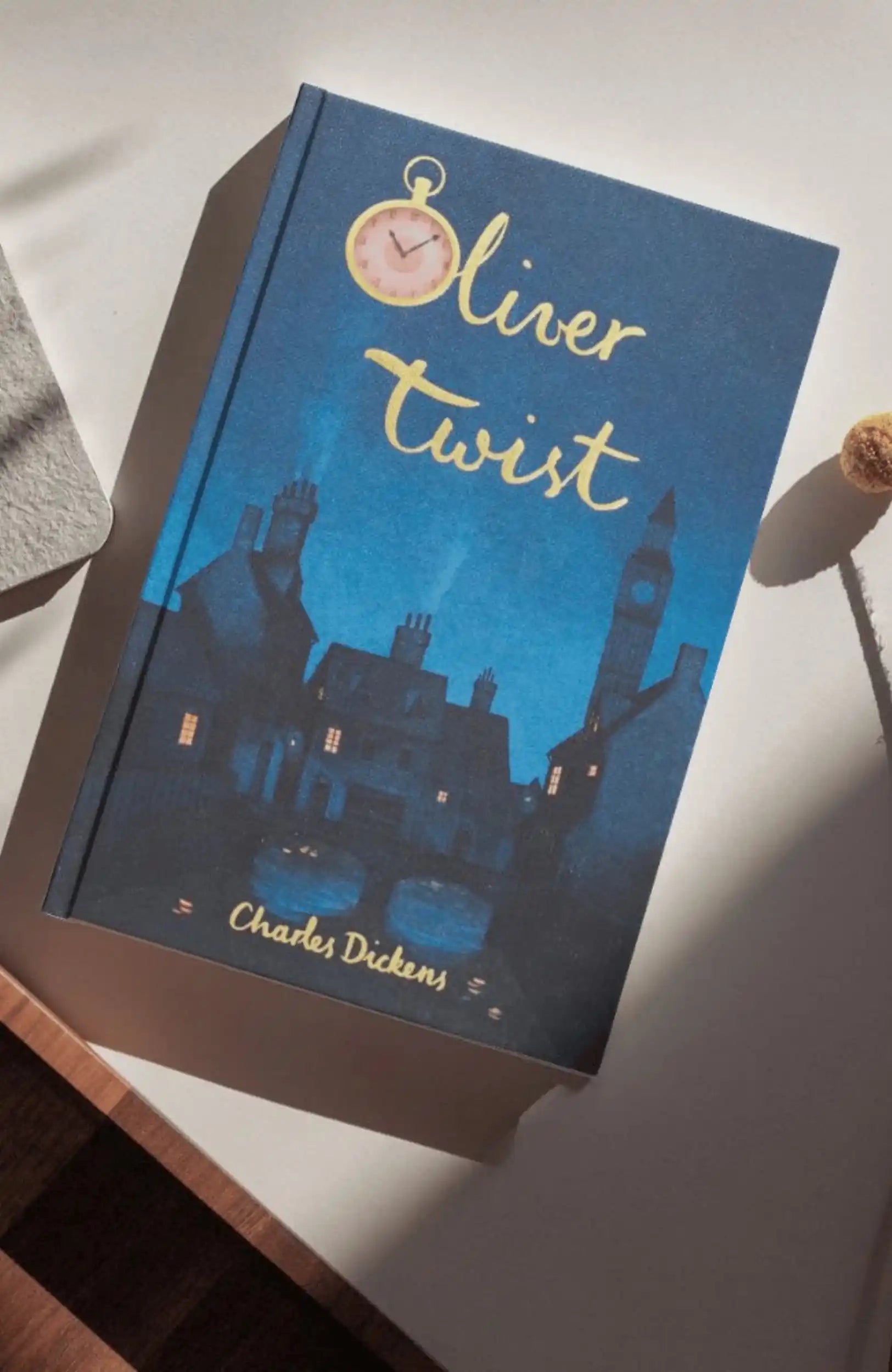 photoshoot of  Oliver Twist collector’s edition hardcover by Charles Dickens with navy blue illustrated cover, gold foil title, cloth-bound finish.