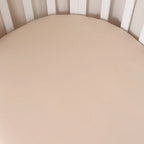 Close up of Babyccino organic cotton fitted cot sheet showing smooth beige jersey fabric and soft breathable texture