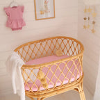Bubblegum pink organic bassinet sheet by Snuggle Hunny on a baby bassinet creating a warm pastel nursery look
