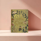 cover of Peter Pan limited collector’s edition hardcover by J.M. Barrie with green illustrated cover, gold foil title, cloth-bound finish and decorative sprayed edges, stacked on books.