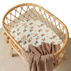 Diggers & Tractors organic bassinet sheet fitted on a woven bassinet in a cosy nursery setting with neutral bedding