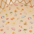 Beach Fun organic cotton bassinet sheet laid flat showing playful beach icons including sun, palm trees and summer details